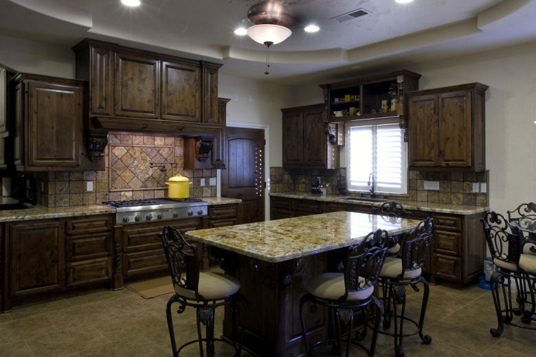 Detail view of custom kitchen cabinetry with decorative range hood and tile backsplash